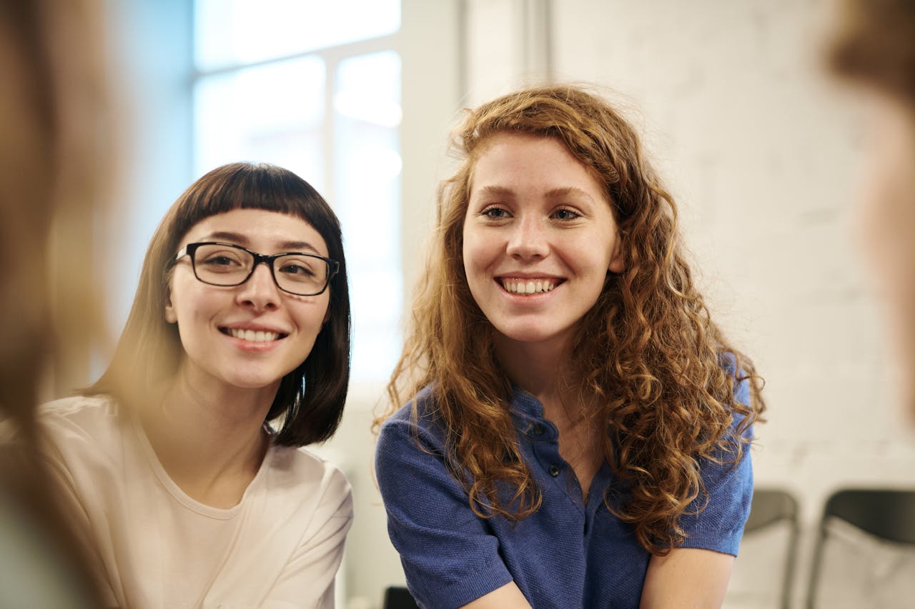 Mastering the First Impression: Your intriguing post title goes here Two smiling young women indoors, conveying friendship and happiness.